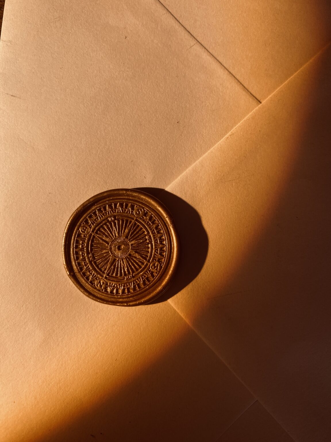 Photo d’un sceau de cire doré représentant une rose des vents, emblème de Circée – Minocha Letters