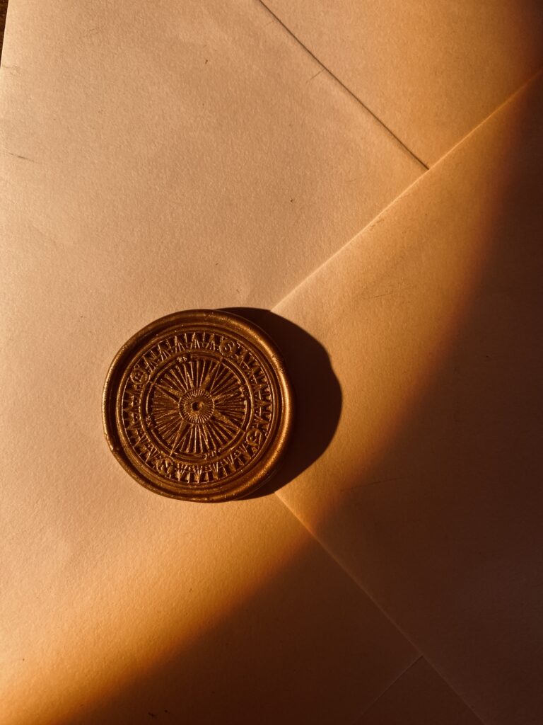 Photo d’un sceau de cire doré représentant une rose des vents, emblème de Circée – Minocha Letters